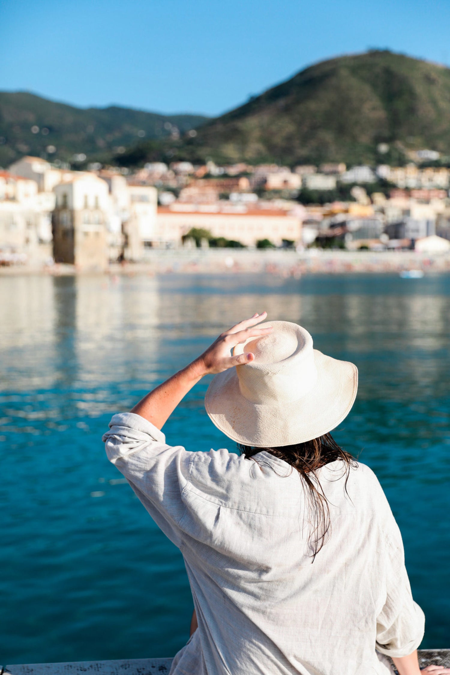 Woman with hat at resort in front of lake.